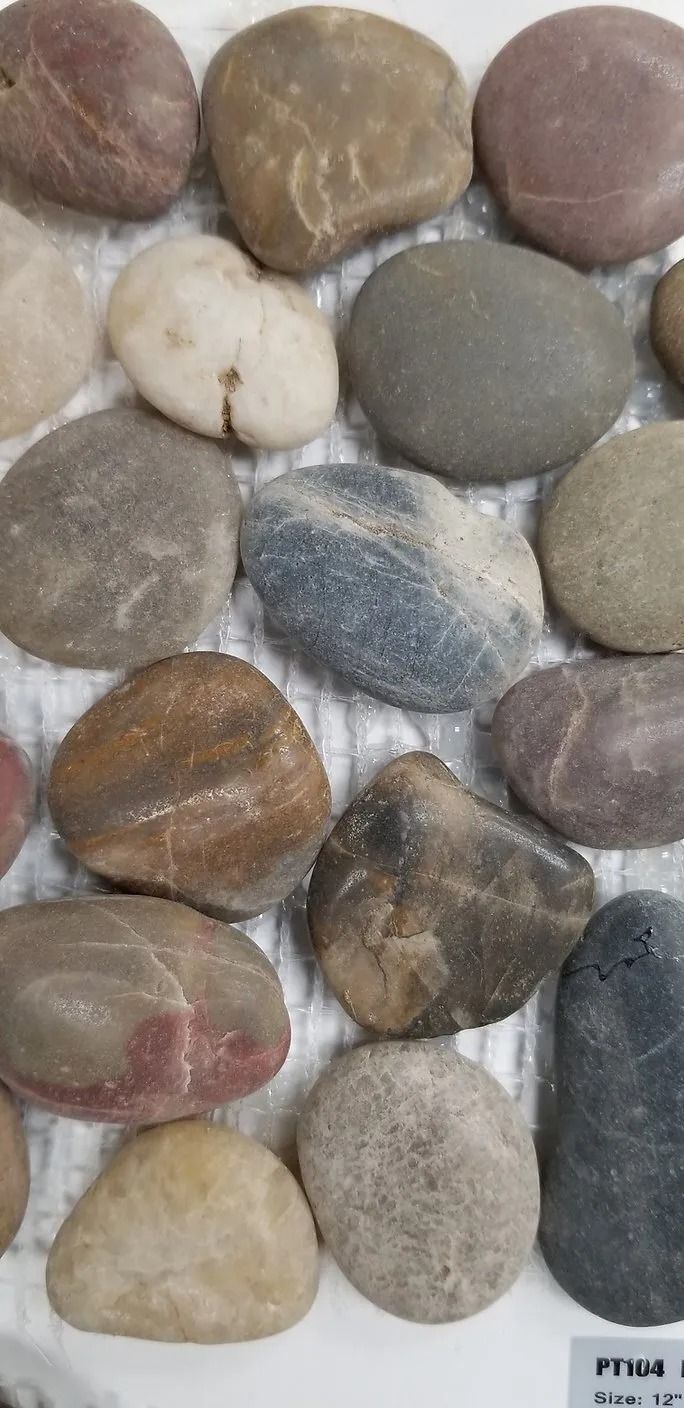 Assorted smooth pebbles in gray, tan, brown, and blue tones arranged closely together