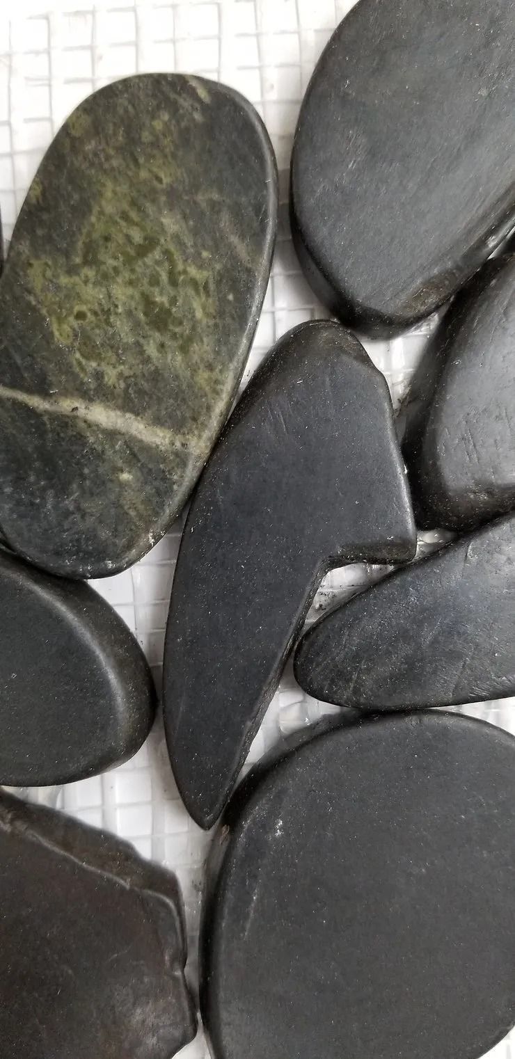 Smooth black and gray pebbles arranged on a white grid surface
