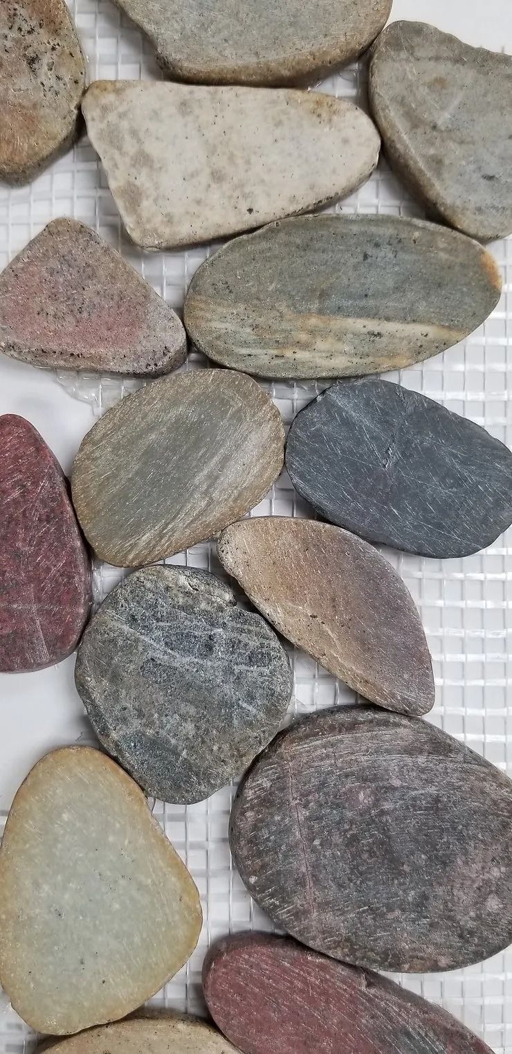 Assorted multicolored smooth pebbles arranged close together on a white background