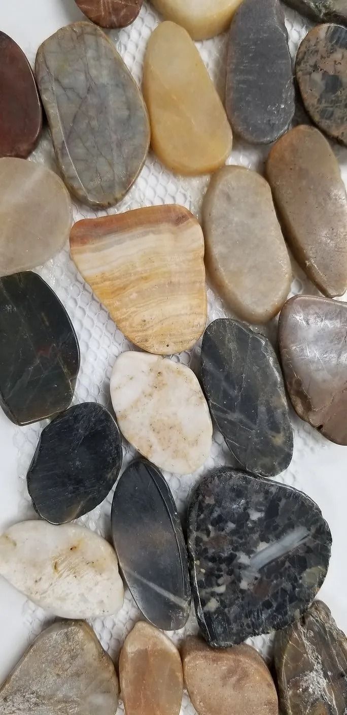 Assorted smooth pebbles in gray, tan, black, and cream tones arranged tightly together