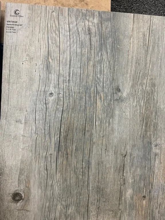 Gray weathered wooden surface with knots and vertical grain lines.