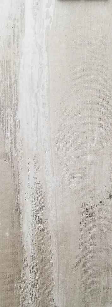 Close-up of a white, weathered wall with vertical stains and peeling texture