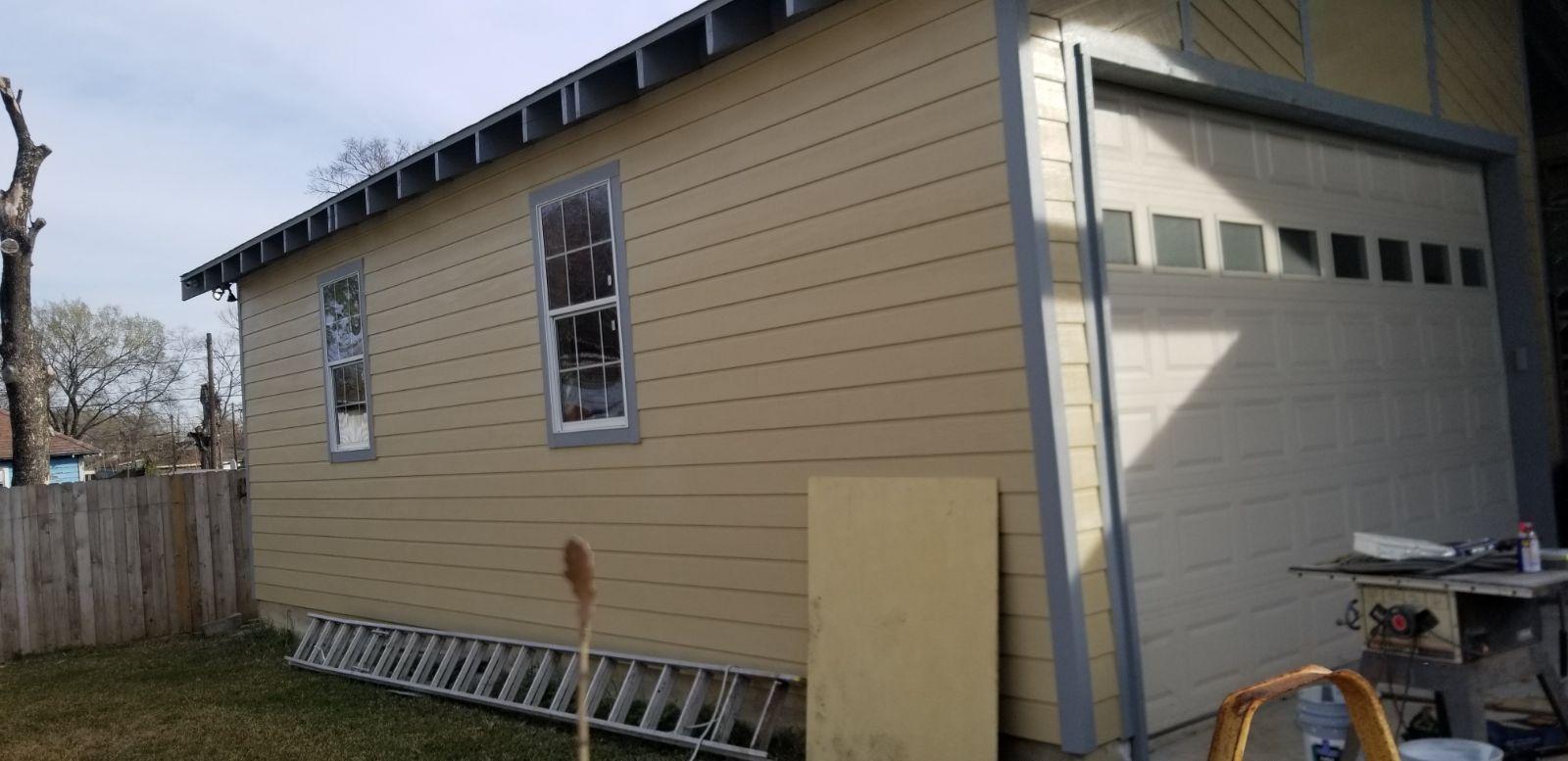 A house with a garage door and a ladder in front of it.