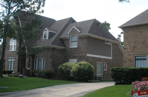 A large brick house with a for sale sign in front of it