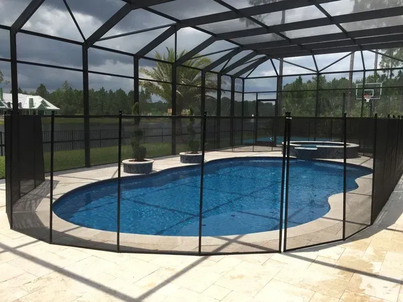 Screened-in backyard pool with blue water and beige patio under a black enclosure.
