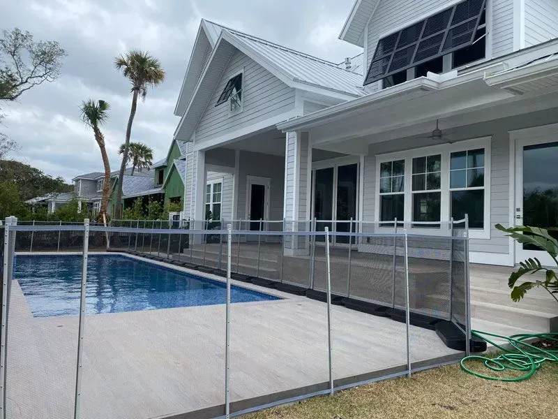 Modern white house with screened pool deck and safety railing beside a blue swimming pool