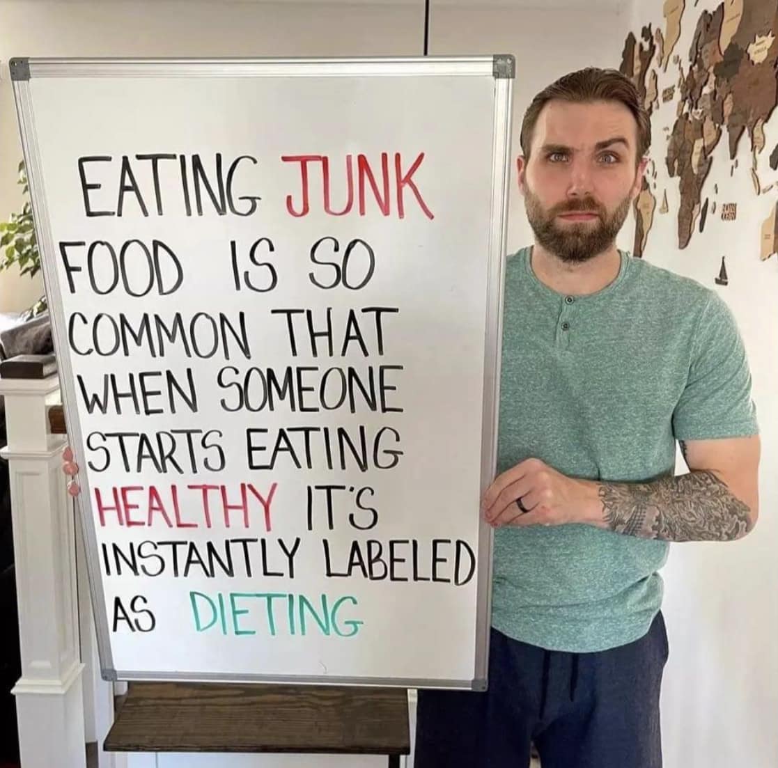 A man standing next to a white board that has a quote about eating junkfood on it