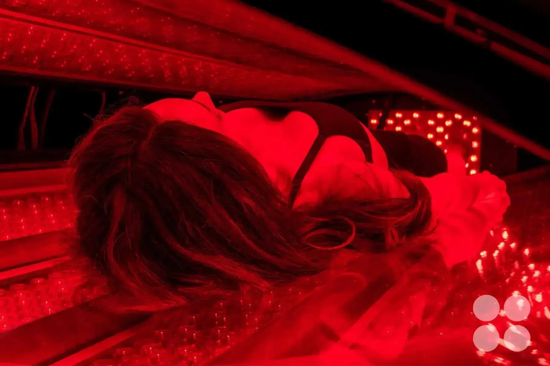 A woman laying in the Max Miracle 9600 red light therapy bed receiving a treatment