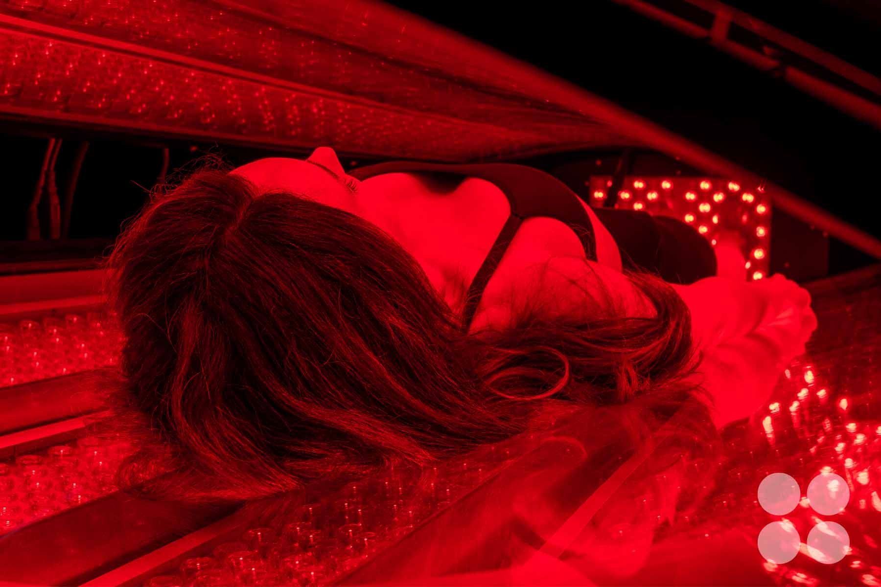 A woman laying in the Max Miracle 9600 red light therapy bed receiving a treatment