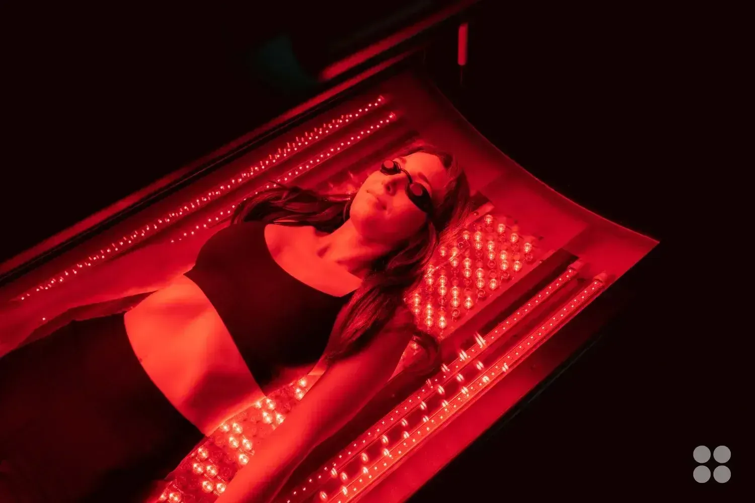 A woman laying in the Max Miracle 9600 red light therapy bed receiving a treatment