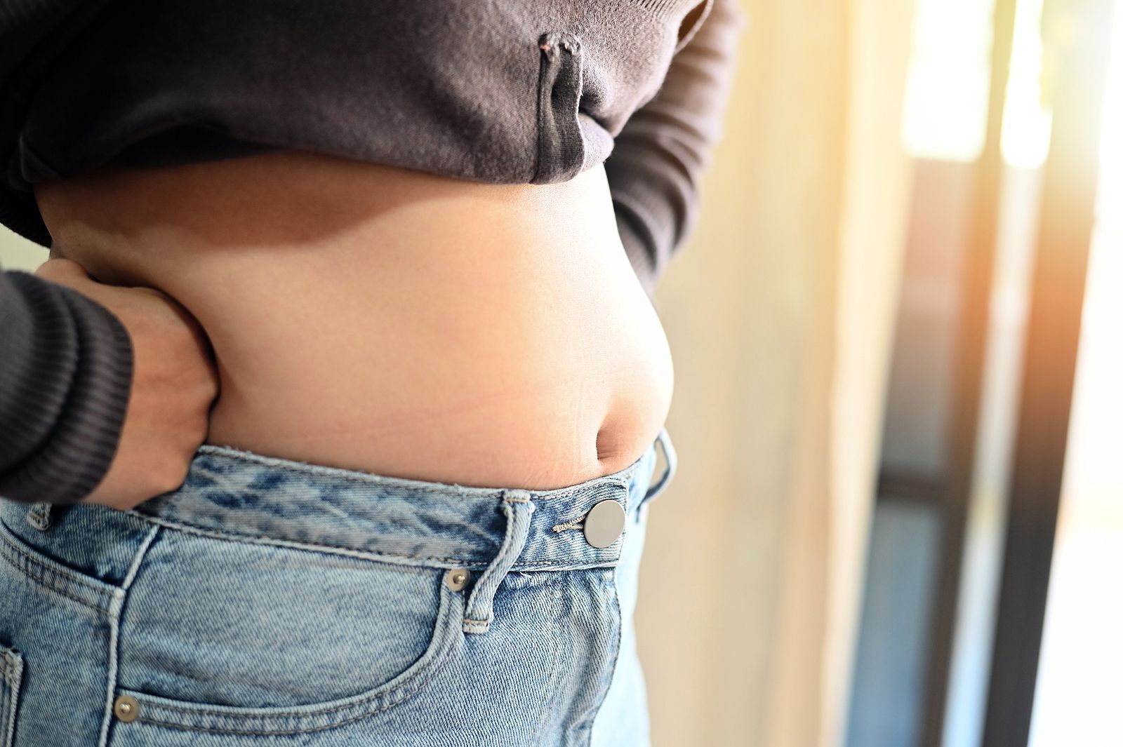 A woman in jeans with her belly fat exposed