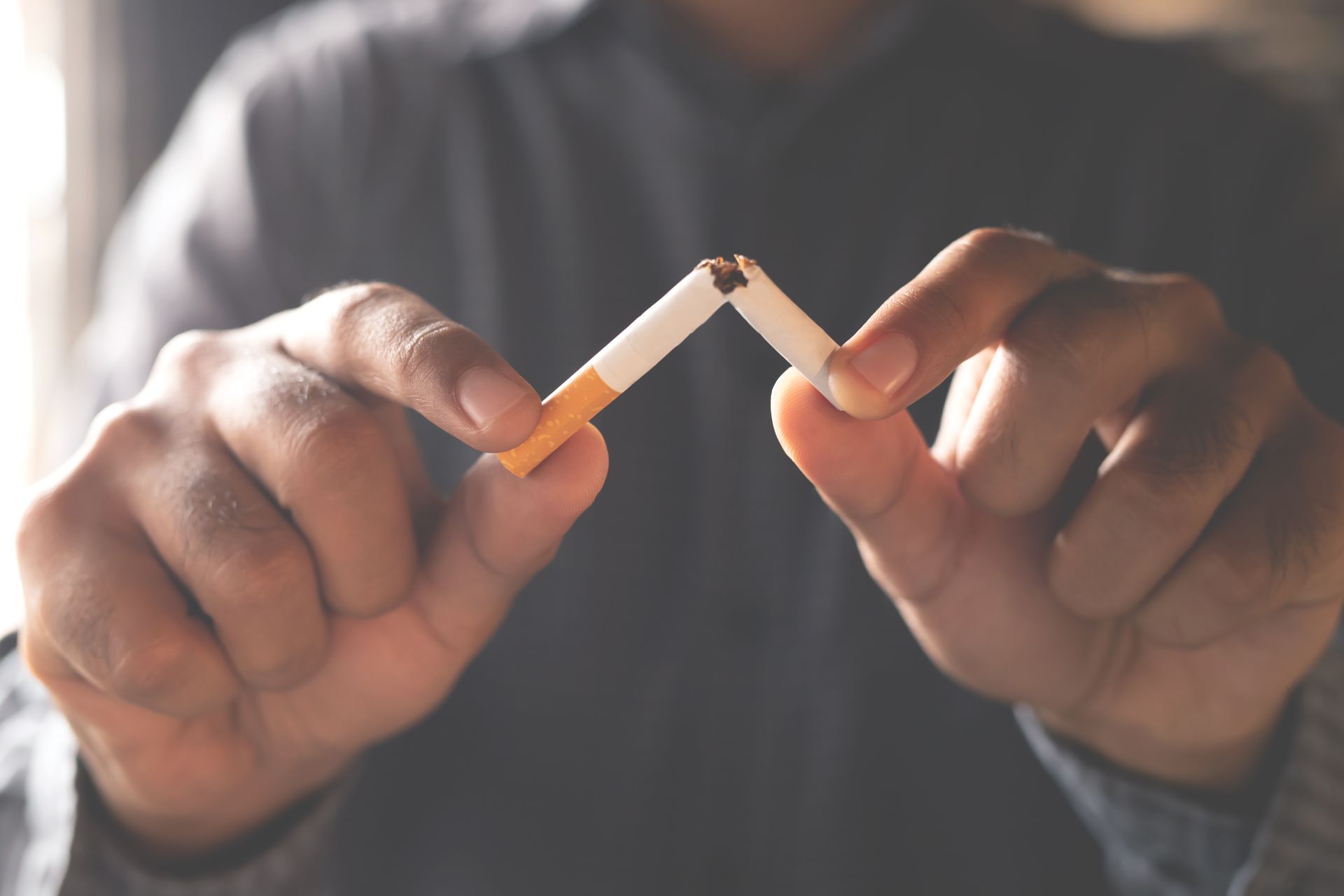 A man breaking a cigarette in half