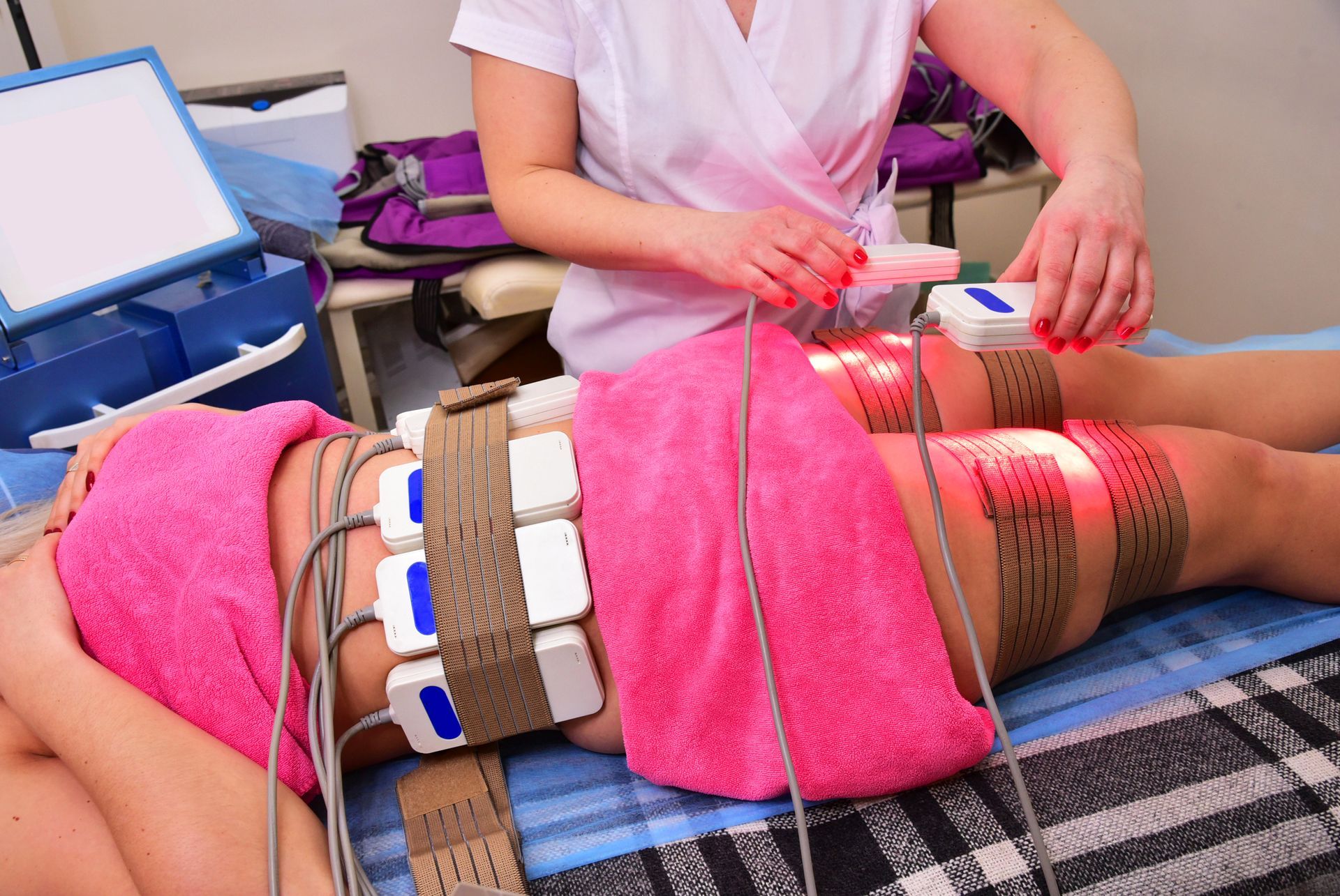 A woman with laser like lipo paddles on her thighs and belly