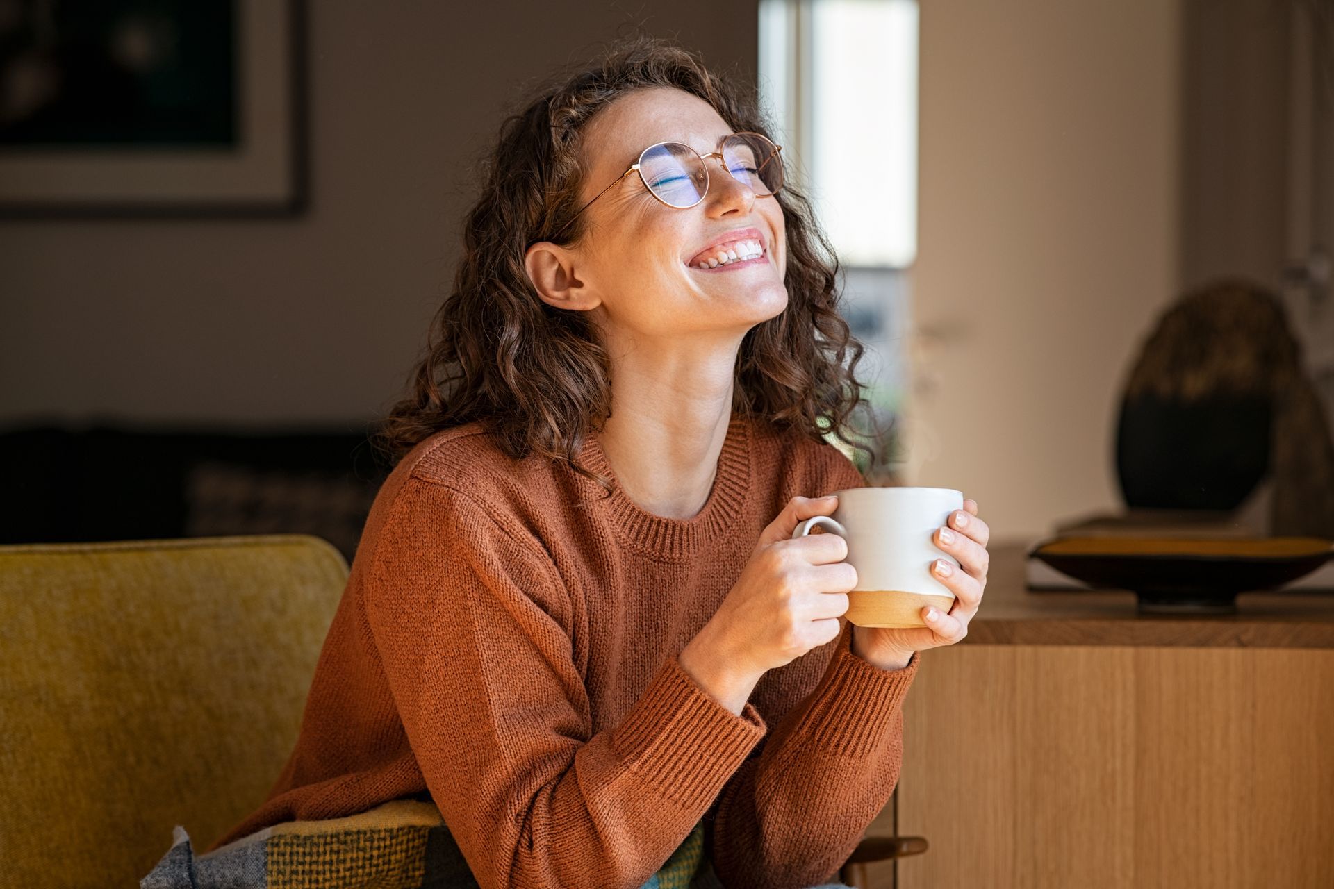 A woman smiling holding a cup of coffee