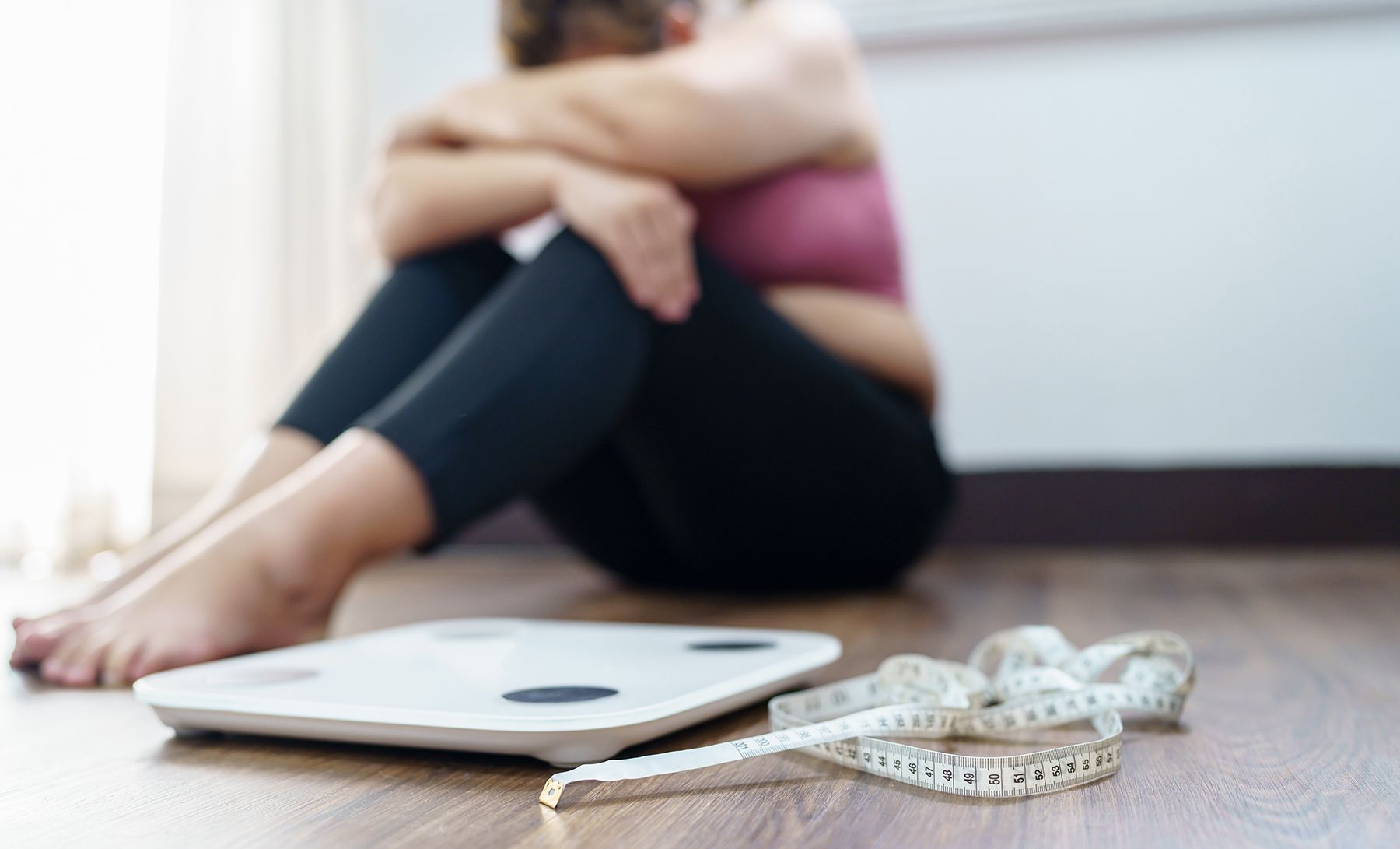 A woman depressed sitting next to a scale