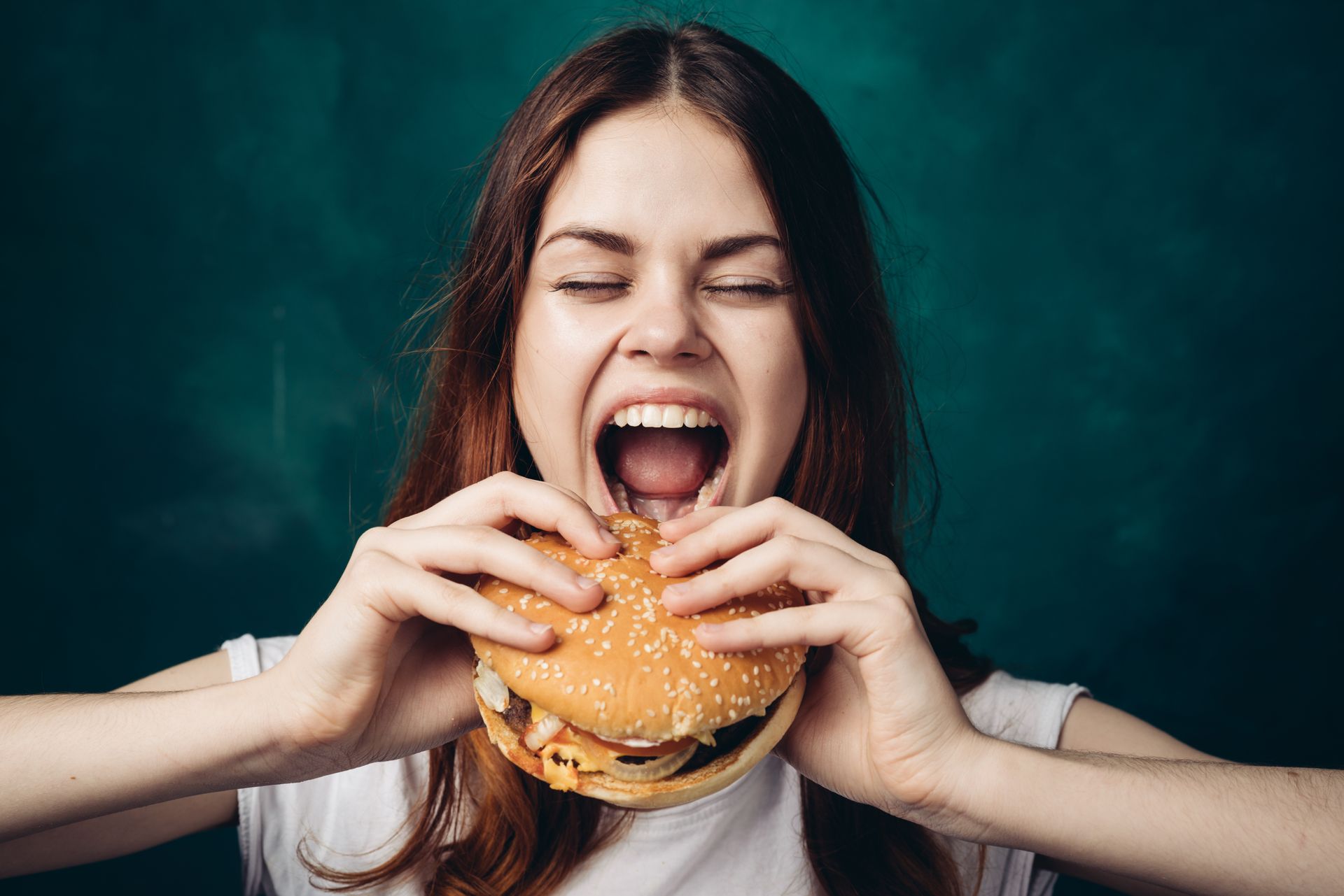 A hungry white woman eating a hamburger