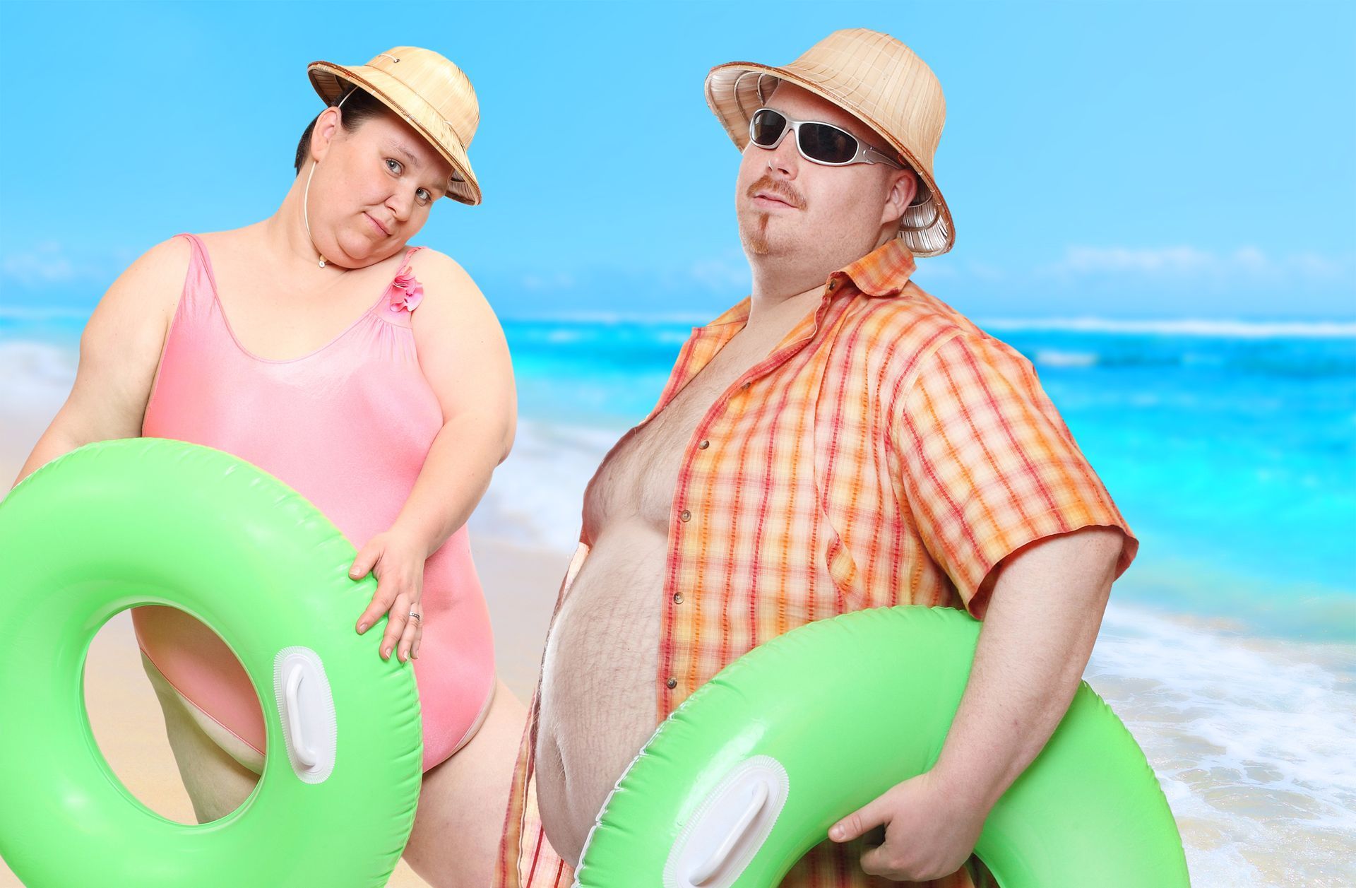 A white man and woman wearing swimsuits with green blow up floaties