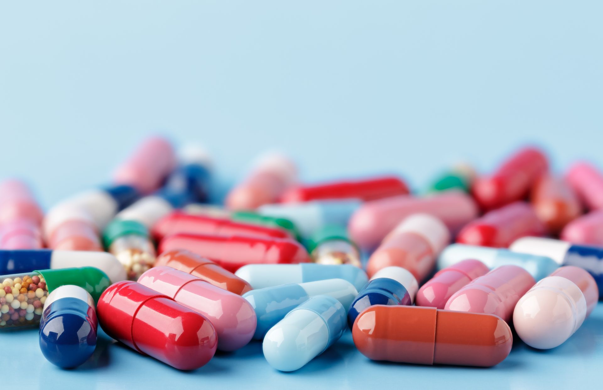 A bunch of different color medication pills sitting on a blue table