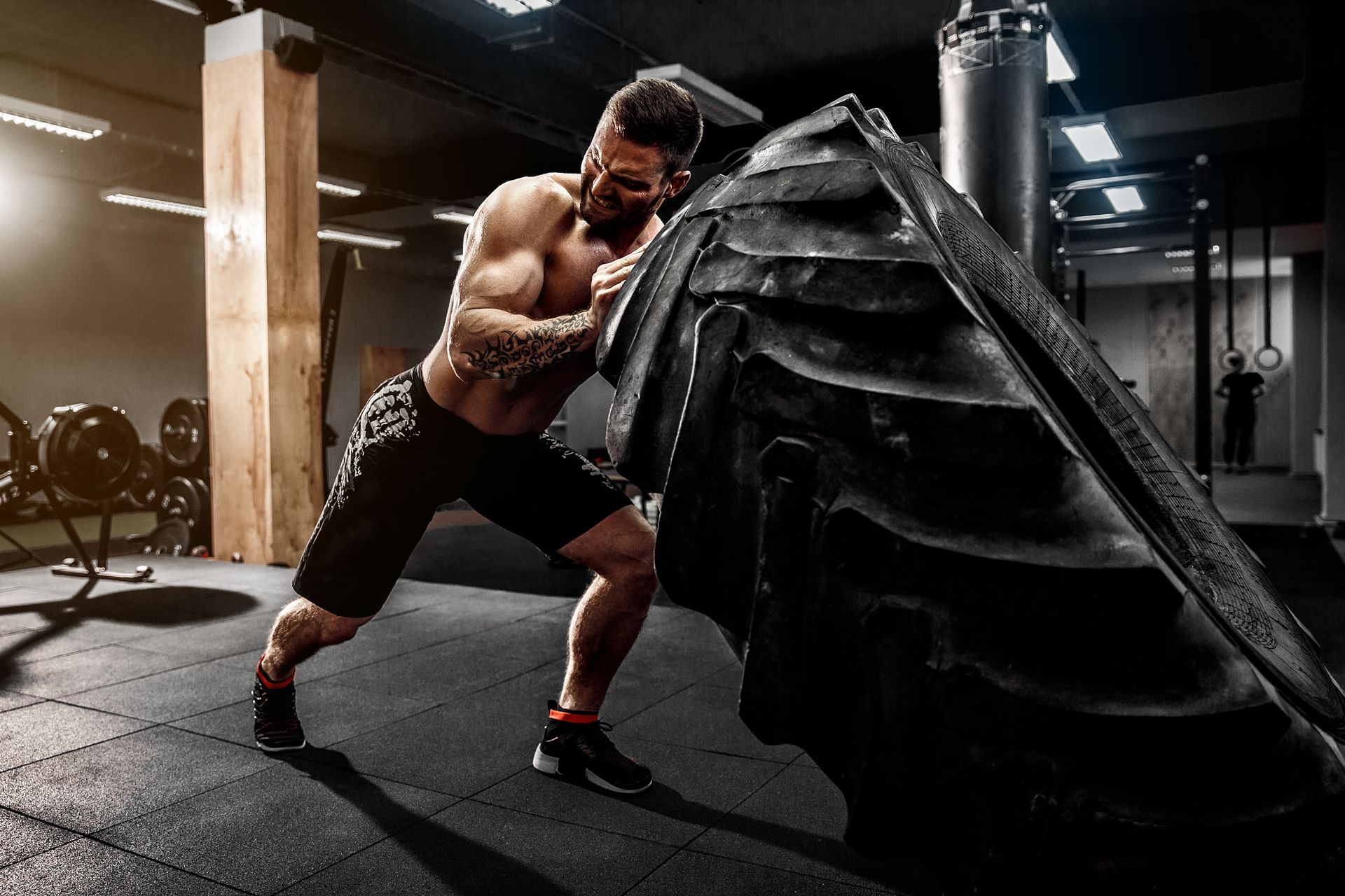 A white man flipping over a tractor tire working out