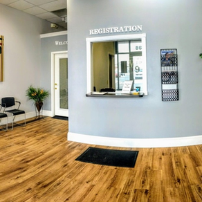 Reception area with wooden floors, registration window, and waiting chairs.