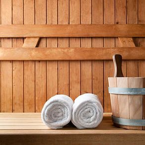 Rolled white towels and wooden bucket in a sauna.