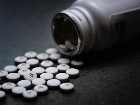 White pills spilling from an overturned medicine bottle on a dark surface.