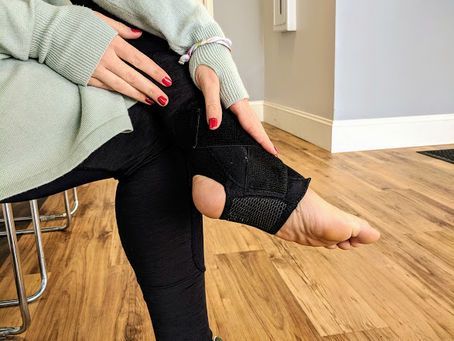 Woman in black stirrup leggings and a mint green sweatshirt; wooden floor.