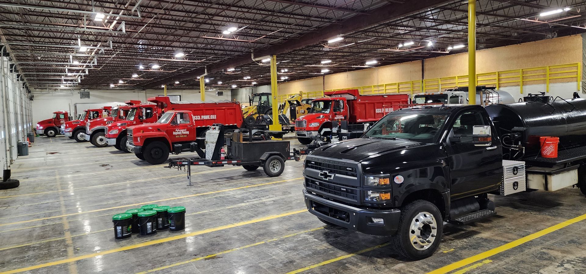 A row of trucks are parked in a large warehouse.