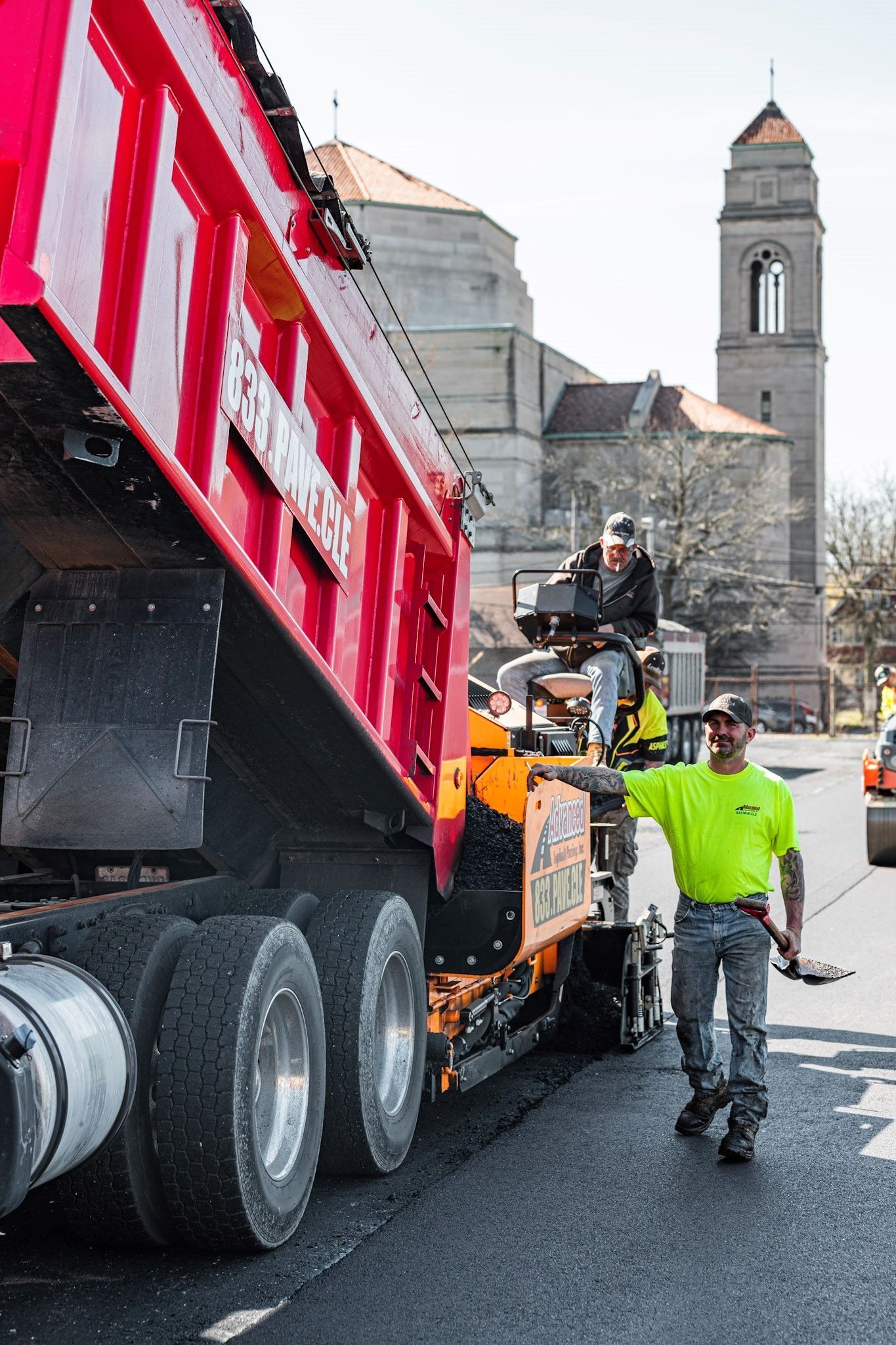 A man in a neon yellow shirt is walking in front of a dump truck