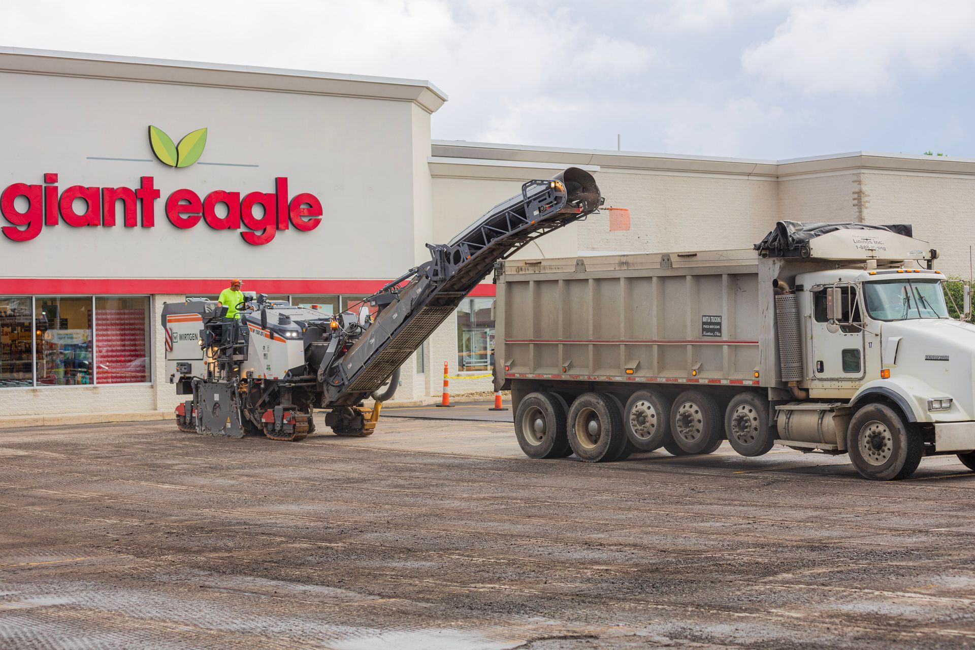 A dump truck is parked in front of a giant eagle store.