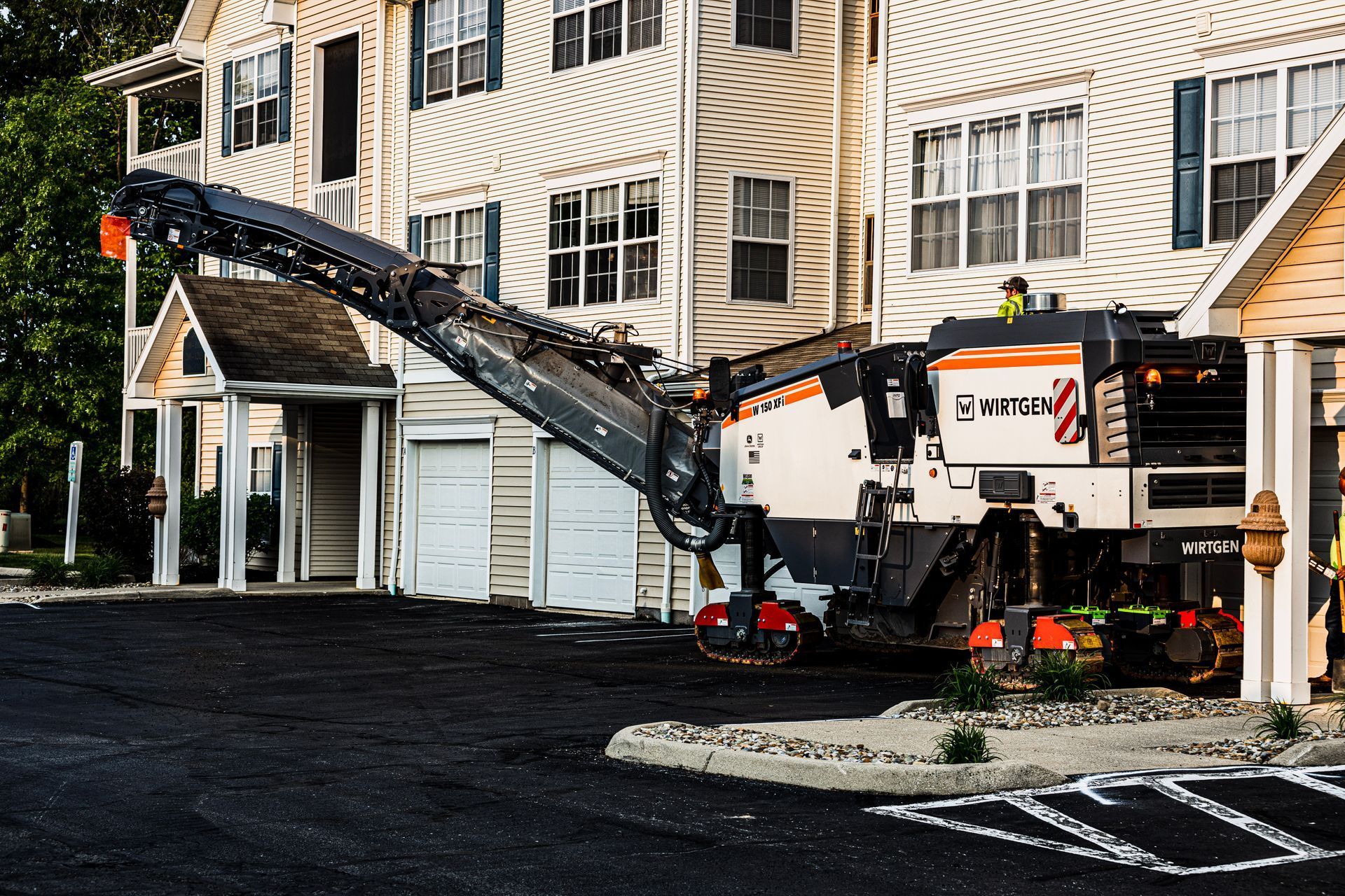 A machine is working on a parking lot in front of a building