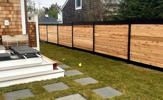 Backyard with wooden fence, lawn, stone pavers, and a small deck by the house