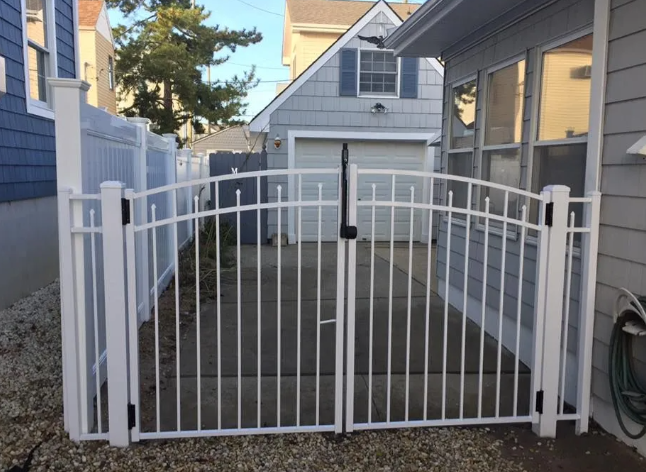 White metal gate across a wooden deck between two houses in a narrow side yard