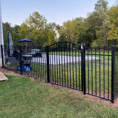 Black metal fence around a backyard patio with blue umbrella and chairs beside a pool area