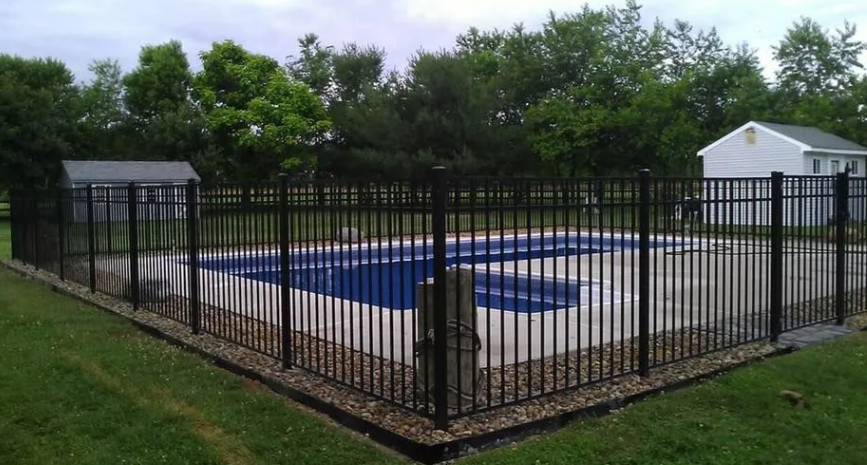 Fenced outdoor swimming pool with blue water and surrounding trees and grass