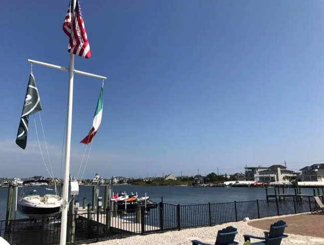 Marina with boats, flagpoles, and clear blue sky over calm water