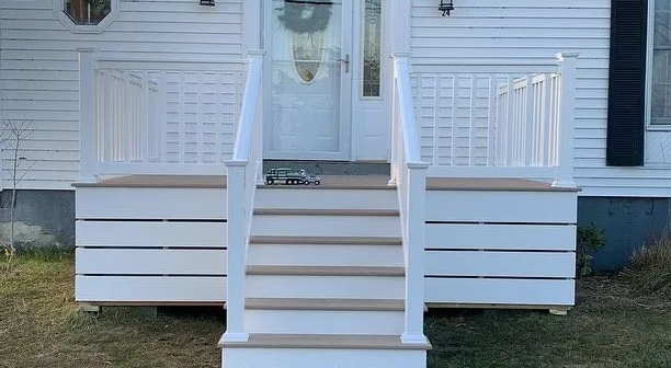 White front porch steps with railings leading to a house entrance and porch seating area