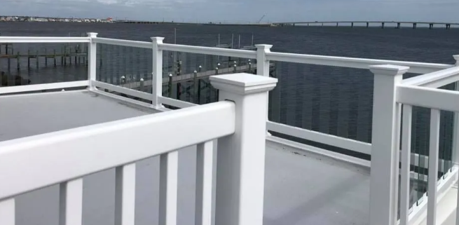 White deck railing overlooking calm water under an overcast sky