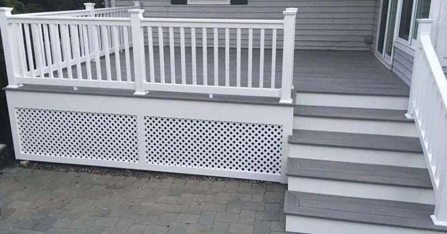 White porch railing and lattice skirting beside gray stairs on a house deck