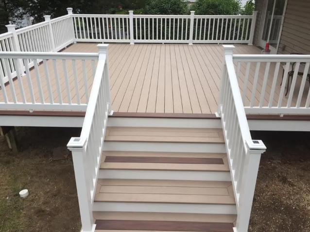 White backyard deck with stairs and railings leading down to a lawn