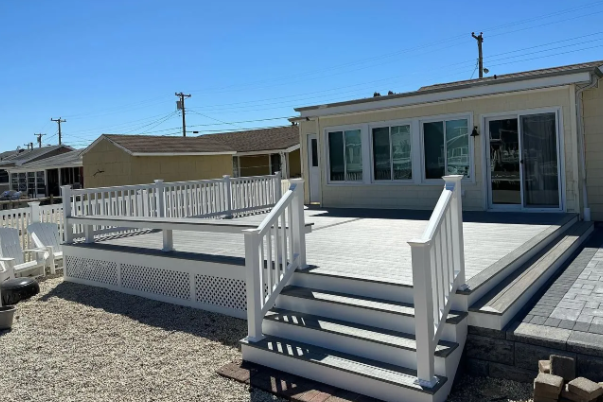 White mobile home porch with ramp, steps, and sliding glass doors on a sunny day