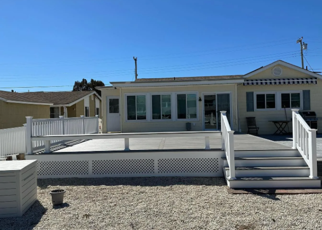 White house with a raised deck and stairs in a sunny desert setting
