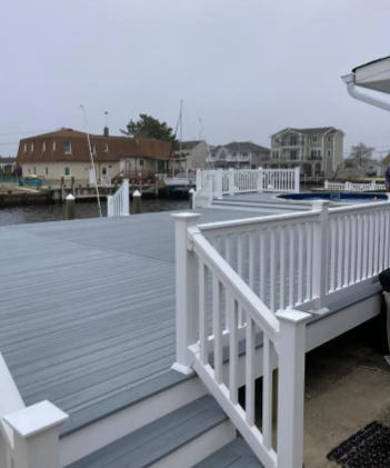 White deck by calm harbor with boats and houses under an overcast sky