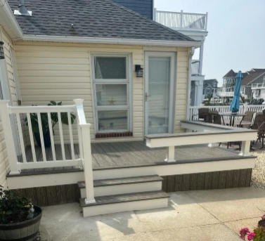 Small beige porch with white railings, steps, and a bench on a coastal house patio.