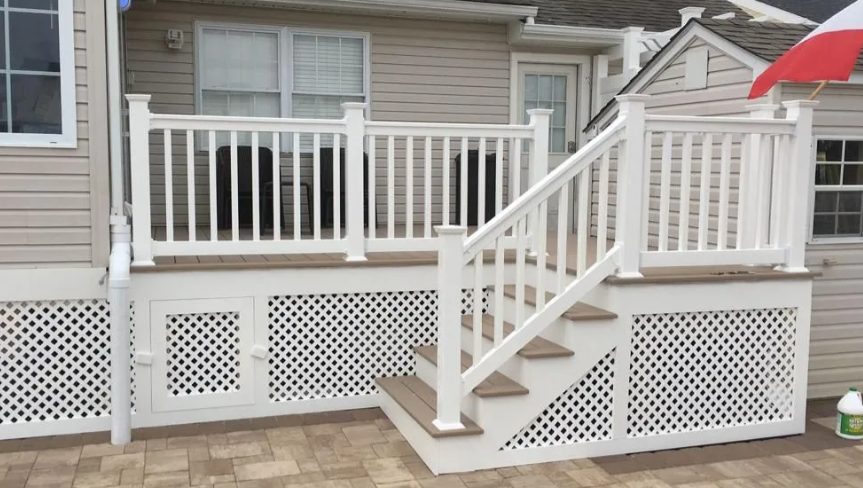 White stairway and railing leading to a raised porch on a beige house with lattice skirting