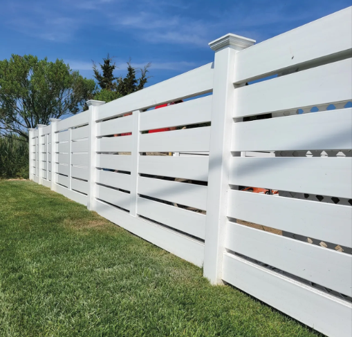 White slat fence bordering a green lawn under a blue sky