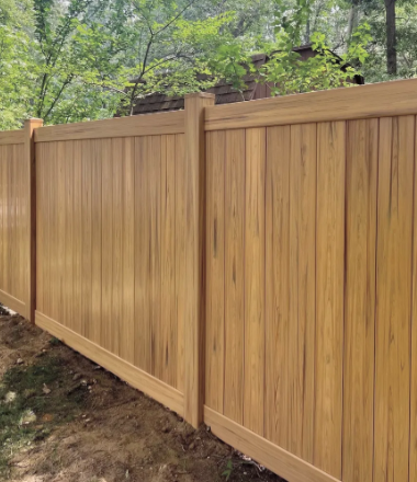 Wooden privacy fence along a wooded yard, with tan panels and posts.