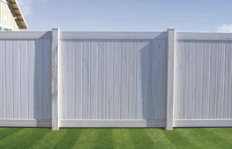 White vinyl privacy fence with gray posts along a green lawn under a blue sky