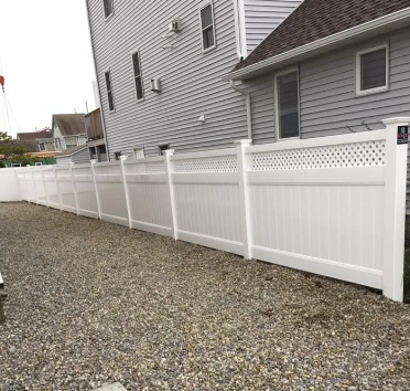 White vinyl privacy fence beside a gray house over a gravel yard