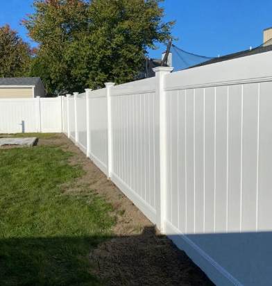 White vinyl fence lining a grassy yard under a clear blue sky